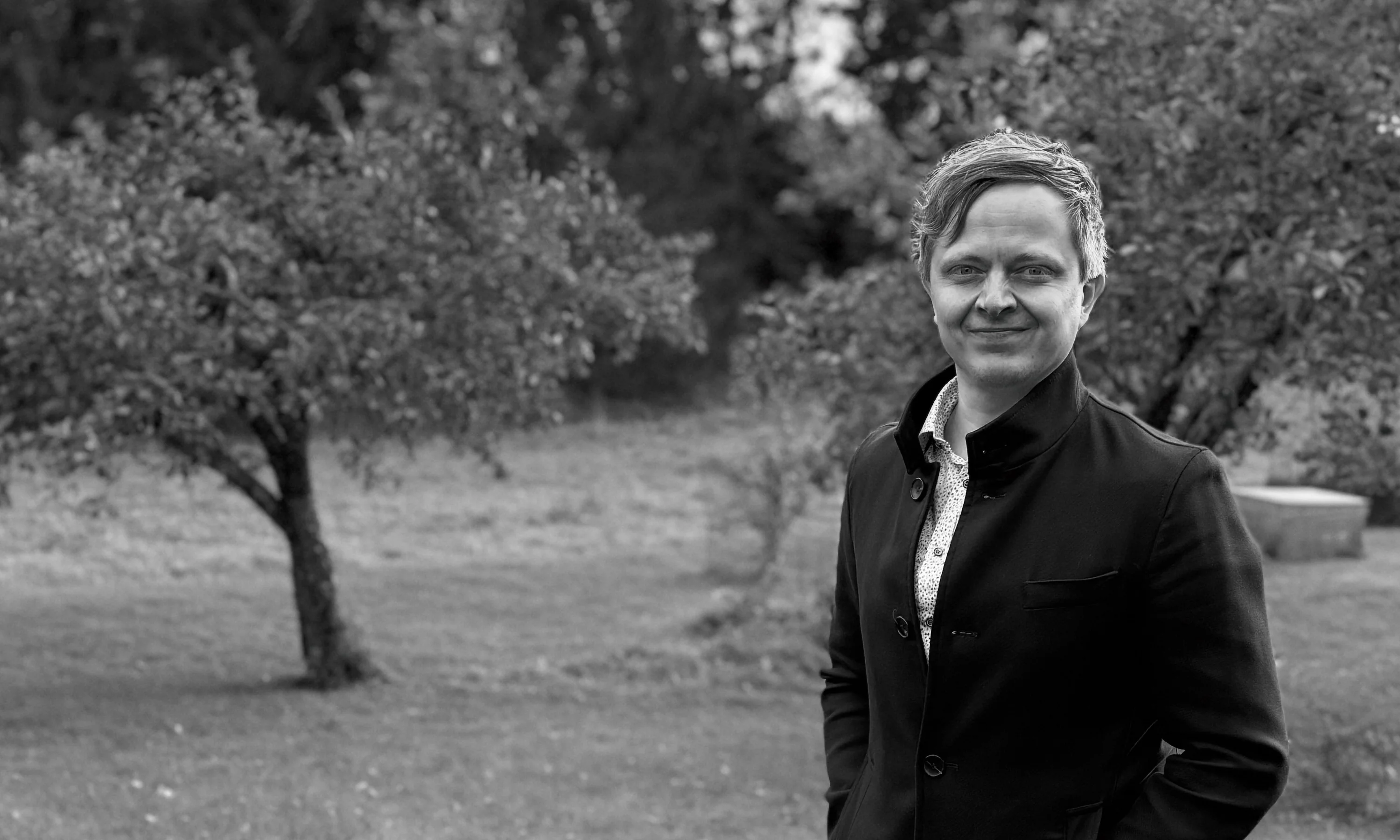 Juha Salo wearing a black coat in a garden